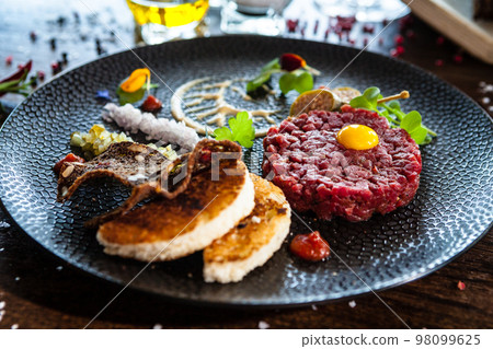 Beef tartare from Black Angus. Onion, quail egg, tomato sauce, mustard mayonnaise. Delicious healthy Italian traditional food closeup served for lunch in modern gourmet cuisine restaurant 98099625