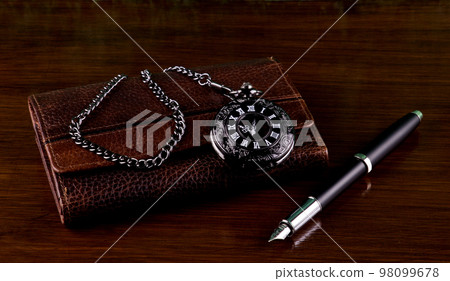 Leather Wallet with Pocket Watch and Fountain Pen on a Wooden Table Top 98099678