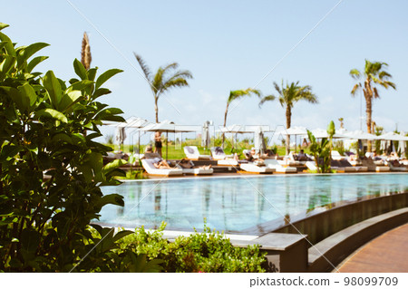 Beautiful luxury umbrella and chair around outdoor swimming pool in hotel and resort with coconut palm tree on blue sky Beautiful luxury umbrella and chair around outdoor swimming pool in hotel and resort with coconut palm tree on blue sky 98099709