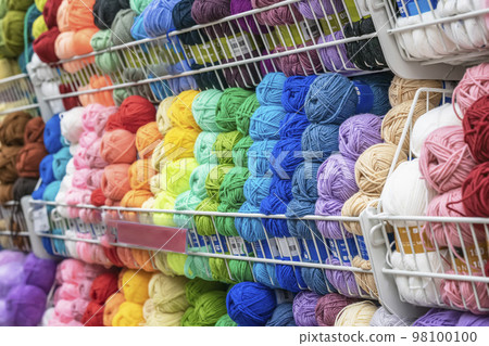 Blurred abstract background of store with colorful yarn for knitting. Store of goods for creativity, needlework, hobby Blurred abstract background of store with colorful yarn for knitting. Store of goods for creativity, needlework, hobby 98100100