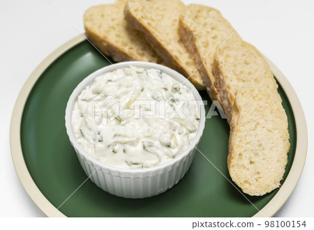 Traditional homemade greek yogurt sauce Tzatziki, tarator in white bowl, grated cucumbers, sour cream yogurt,olive oil,garlic,herbs on plate with sliced bread, white background.Horizontal Traditional homemade greek yogurt sauce Tzatziki, tarator in white bowl, grated cucumbers, sour cream yogurt,olive oil,garlic,herbs on plate with sliced bread, white background.Horizontal 98100154