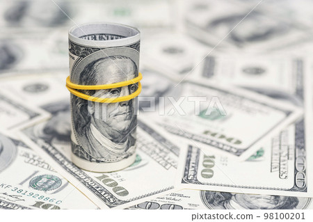 A roll of 100 dollar bills close-up on a pile of American dollars A roll of 100 dollar bills close-up on a pile of American dollars 98100201