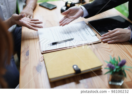Lawyer hands important documents to couple to sign. 98100232