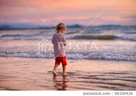 Child playing on ocean beach. Kid at sunset sea. Child playing on ocean beach. Kid at sunset sea. 98100426