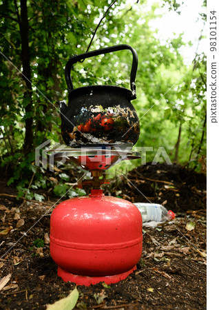 Heating water with a gas cylinder in the forest during a rest in the forest. 98101154
