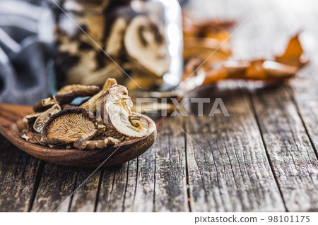 Sliced dried mushrooms in wooden spoon on wooden table. Sliced dried mushrooms in wooden spoon on wooden table. 98101175