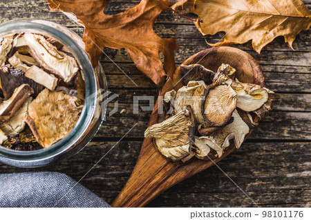 Sliced dried mushrooms in wooden spoon on wooden table. Top view. Sliced dried mushrooms in wooden spoon on wooden table. Top view. 98101176