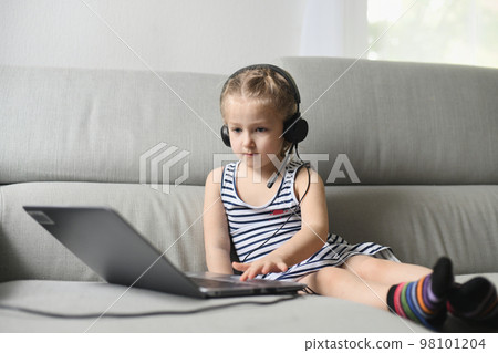 Girl in headphones play with computer of parents Girl in headphones play with computer of parents 98101204