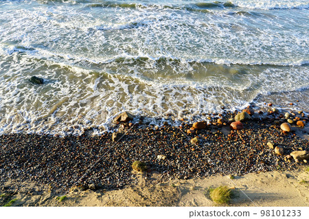Beautiful view of rocky Baltic Sea coast, sand dune and waves with white foam tops in sunset light Beautiful view of rocky Baltic Sea coast, sand dune and waves with white foam tops in sunset light 98101233