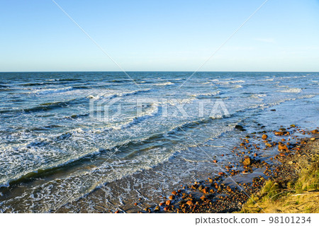 Beautiful view of rocky Baltic Sea coast, sand dune and waves with white foam tops in sunset light Beautiful view of rocky Baltic Sea coast, sand dune and waves with white foam tops in sunset light 98101234