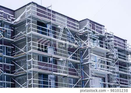 Scaffolding around an apartment building under renovation is covered with hoarfrost during winter 98101238