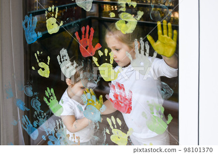 The kids paint with palms on the window. Quarantine The kids paint with palms on the window. Quarantine 98101370