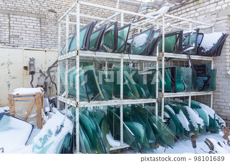 Metal shelving with used windshields removed from disassembled cars for their further sale. Metal shelving with used windshields removed from disassembled cars for their further sale. 98101689