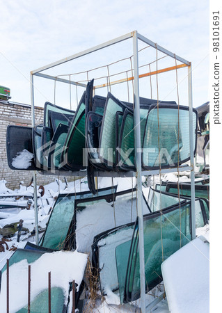 Metal shelving with used windshields removed from disassembled cars for their further sale. Metal shelving with used windshields removed from disassembled cars for their further sale. 98101691