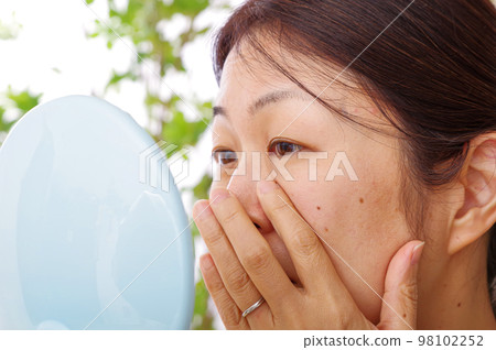 A woman in her 40s who is concerned about the details of her face A woman in her 40s who is concerned about the details of her face 98102252