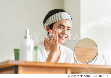 年輕人在臉上塗保濕霜 年輕人在臉上塗保濕霜 98102304