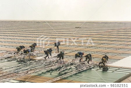 冒著生命危險工作的人們懸掛在垂直向天空延伸的建築物上。 98102551