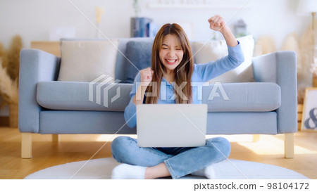 Young asian woman in good spirits working on laptop at home Young asian woman in good spirits working on laptop at home 98104172