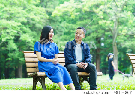 Young couple chatting on a park bench Young couple chatting on a park bench 98104867