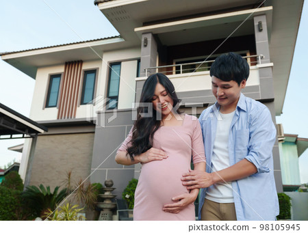 happy family standing outside house and looking belly, husband and pregnant wife happy family standing outside house and looking belly, husband and pregnant wife 98105945