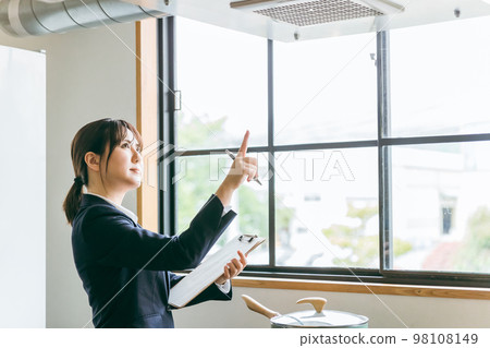 Asian businesswoman checking ventilation fan in kitchen 98108149