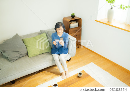 Senior woman doing online shopping with a credit card 98108254