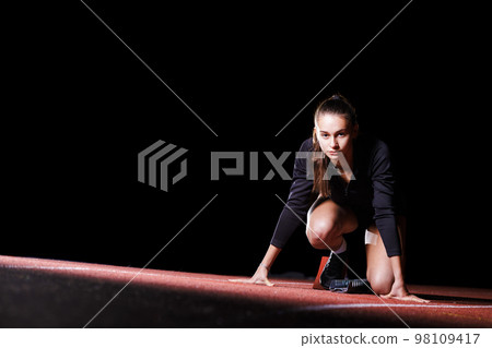 Young sportswoman at the starting blocks before running sprint 98109417