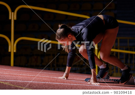 Young sportswoman at the starting blocks before running sprint Young sportswoman at the starting blocks before running sprint 98109418