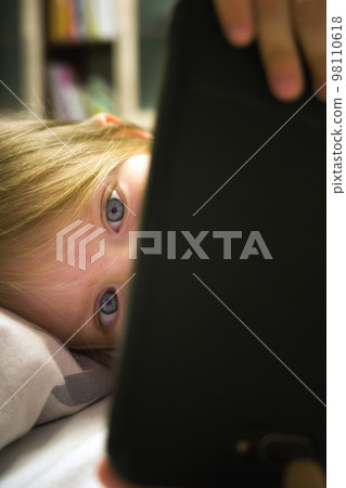 Small kidl looking on smartphone screen. Child mobile phone addiction 98110618