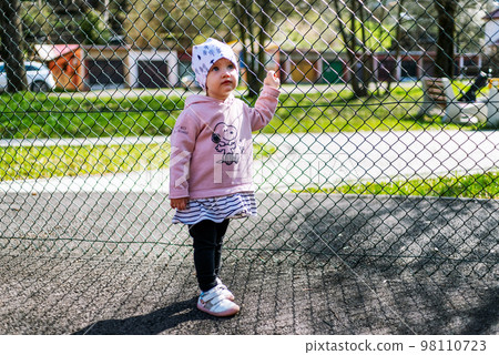 Small girl toddler holding fence Small girl toddler holding fence 98110723