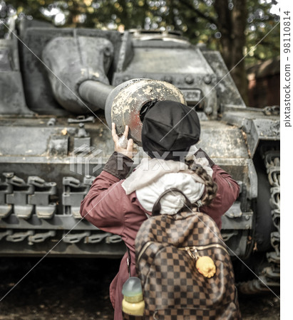 Girl looking into to barrel of old tank 98110814