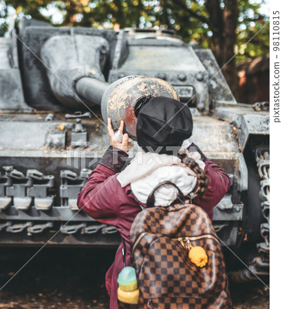 Girl looking down the barrel of old tank 98110815