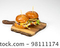 Two fresh homemade burgers on wooden serving board. White background with copy space Two fresh homemade burgers on wooden serving board. White background with copy space 98111174