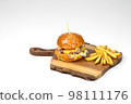 Fresh homemade hamburger on wooden serving board with fries. White background with copy space Fresh homemade hamburger on wooden serving board with fries. White background with copy space 98111176