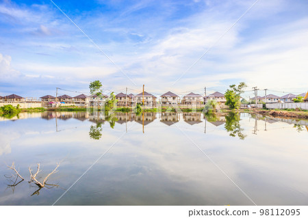 New house building reflection with water in lake at residential estate construction site with clouds and blue sky New house building reflection with water in lake at residential estate construction site with clouds and blue sky 98112095