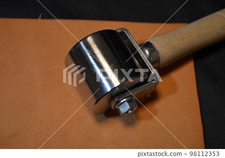Close-up photo of crimping rollers placed on natural leather Close-up photo of crimping rollers placed on natural leather 98112353