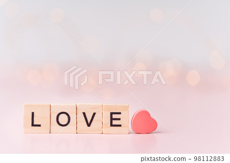Word love is lined with wooden letters next to heart against blurred pink background 98112883