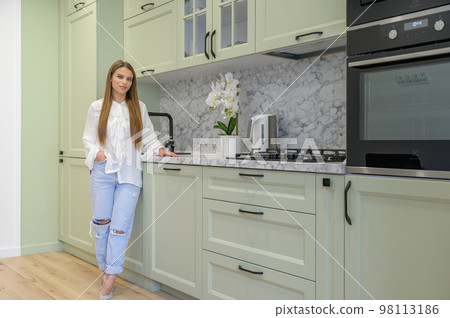 Portrait of young cute housewife in the kitchen interior 98113186