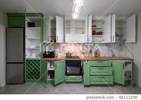 Doors open and drawers pulled out at new green and white kitchen furniture 98113290