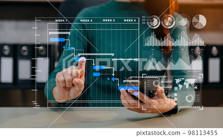 Businessman hand Project manager working and update tasks and Gantt chart scheduling virtual diagram.with smart phone, tablet and laptop in office.. 98113455