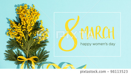 Spring mimosa branches with a yellow ribbon flat lay on blue background 98113523
