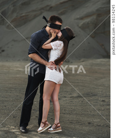 Romantic couple blindfolded with black ribbon kissing outdoors. Love blind concept Romantic couple blindfolded with black ribbon kissing outdoors. Love blind concept 98114245