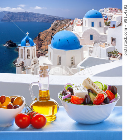 Greek food against famous churches in Oia village on Santorini island in Greece 98114292