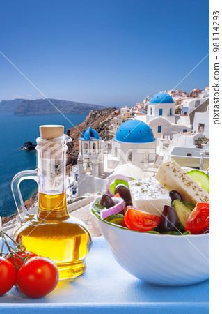 Greek food against famous churches in Oia village on Santorini island in Greece 98114293