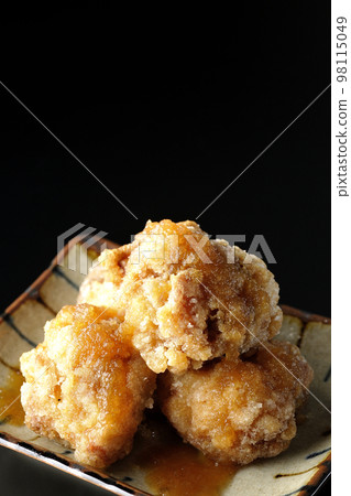 Tatsuta-age chicken with ponzu sauce and grated daikon radish on a black background 98115049