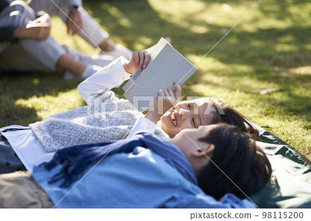 little asian children lying on grass reading 98115200