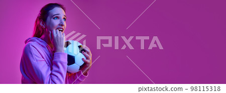 Tense feelings. Portrait of young emotive girl posing with football ball background in neon light. Banner, flyer. Concept of emotions, youth, lifestyle Tense feelings. Portrait of young emotive girl posing with football ball background in neon light. Banner, flyer. Concept of emotions, youth, lifestyle 98115318