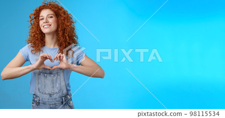 Sassy confident good-looking modern redhead curly woman raise head proud love tell girlfriend romantic heartwarming feelings present own heart smiling broadly standing blue background Sassy confident good-looking modern redhead curly woman raise head proud love tell girlfriend romantic heartwarming feelings present own heart smiling broadly standing blue background 98115534