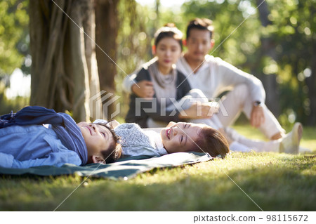 asian family with two children relaxing in park asian family with two children relaxing in park 98115672