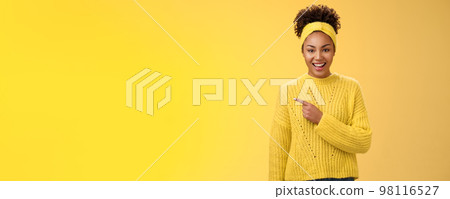 Friendly good-looking enthusiastic black charming girl in headband sweater smiling broadly amused pointing left awesome place showing you perfect blank space advertisement, posing yellow background Friendly good-looking enthusiastic black charming girl in headband sweater smiling broadly amused pointing left awesome place showing you perfect blank space advertisement, posing yellow background 98116527